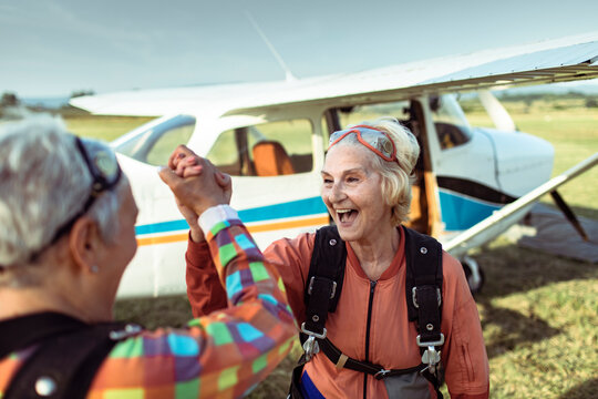 Two senior women laughing after skydiving adventure at sunset
