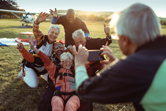 Diverse senior friends taking group photo after skydiving