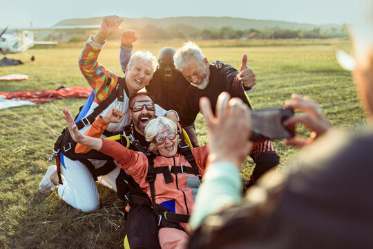 Diverse senior friends taking group photo after skydiving