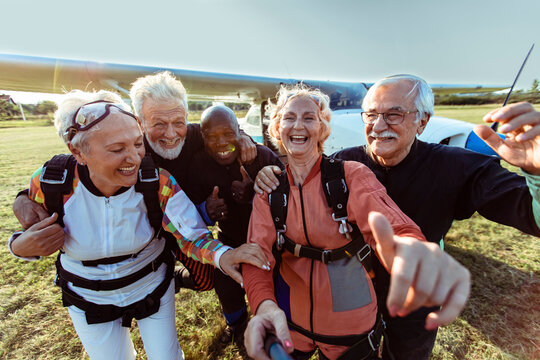 Diverse senior friends taking group photo after skydiving