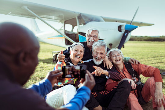Diverse senior friends taking group photo after skydiving