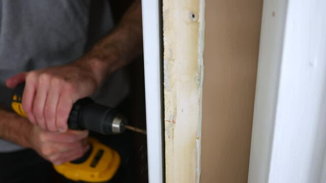 Contractor drills into door jamb installing prehung door for remodel