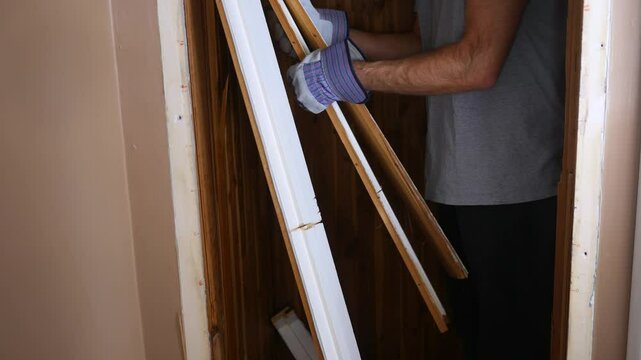 Contractor collects broken wood from old door jamb