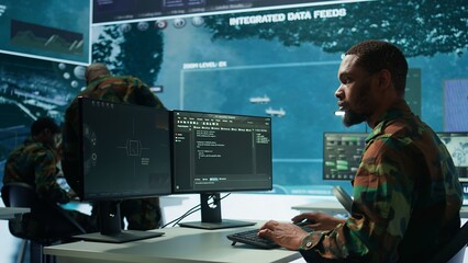 Military specialist in a high tech control center managing satellite radar surveillance, collecting...