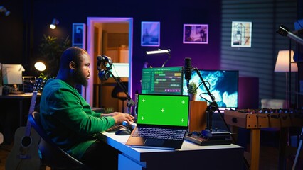 Producer editing his audio files and recordings on digital pc interface, sitting next to an...