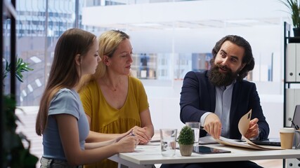 Obraz premium Financial advisor meeting with clients to counsel them on their finances, making list of steps to achieve comfortable income. Agent creating budget for customers, giving investing advice, camera B