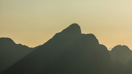 Silhouettes of huge karst mountains covered in rainforest, at sunset, near Vang Vieng, in Laos