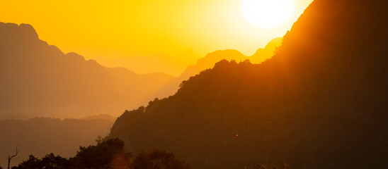 The sky and landscape are tinged with intense orange, with all kinds of particles floating in the air, almost like a dream, near Vang Vieng, Laos, Southeast Asia