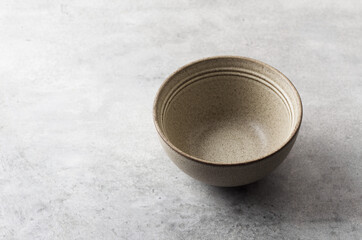 Simple empty beige craft ceramic bowl on a gray textured background, mockup, for graphic design, creativity