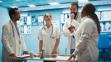 Team of medical specialists examining diagnostic data and hospital records, using a holographic image in cabinet. Experts looking into treatment plans on hologram at clinic. Camera B.