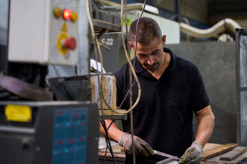 Metalworker finishing mechanical part in factory workshop