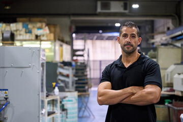 Supervisor posing with arms crossed in metalworking factory