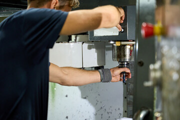 Metalworker operating cnc milling machine in factory