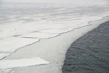 The ice-free Angara River flows out of the frozen Lake Baikal. Melted ice floes on blue water.  Located Baikal lake.