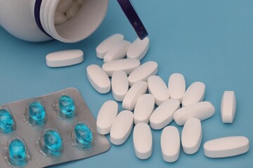 white tablets and a blister with blue capsules