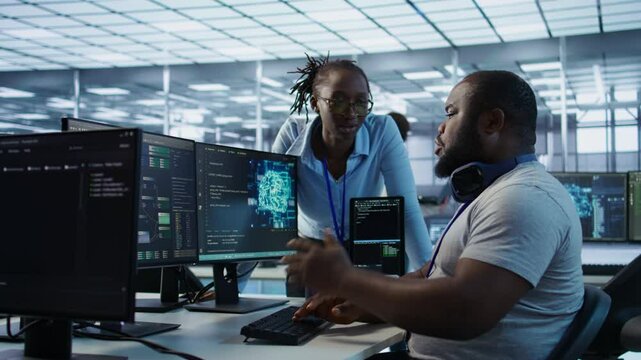 System administrator working with colleague in data center providing computing resources for different workloads. IT specialist talking with coworker while monitoring AI supercomputers, camera B