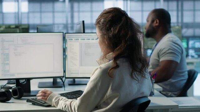 Employee sitting next to african american coworkers in data center doing checkup on electronics to avoid downtime. Engineer and colleagues supervising server room infrastructure components, camera A