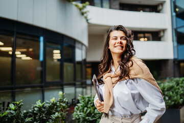 Young businesswoman going to work in front of modern business building	
