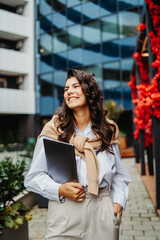 Young businesswoman going to work in front of modern business building	