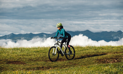 Naklejka premium Asian woman riding mountain bike on beautiful mountain top