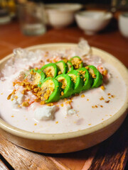 Traditional Indonesian Dessert from South Sulawesi. Pisang Ijo served in a wide bowl. Sweet banana wrapped in green dough with coconut sauce.