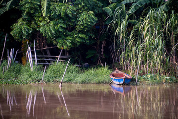 Small wooden boat floating on the brown water river. Beautiful landscape background at Cisadane River, Tangerang, Banten, Indonesia