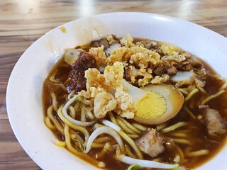 Singapore Hawkers Food local singapore food Lor mee or braised noodles . It comes in a thick gravy topped with slices of pork, tofu, fish cake, and egg served with a dash of black vinegar