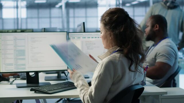 Employee overseeing server room, reading documentation paperwork, troubleshooting hardware. Supervisor doing inspection in server hub, reading technical files at computer desk, camera A