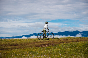 Obraz premium Asian woman riding mountain bike on beautiful mountain top