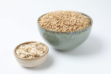 Oat grains and flakes in bowls isolated on white