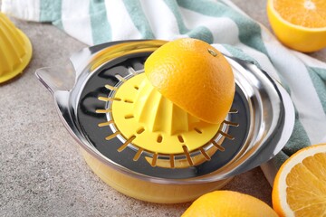 Juicer and oranges on grey table, closeup