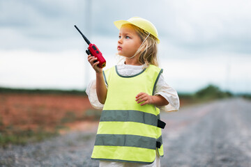young girl wearing a yellow vest and holding a walkie talkie