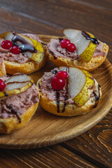 toast with chicken liver pate with pear, cranberry and sauce on a wooden table