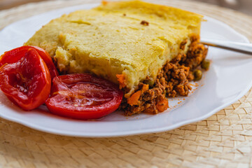 freshly prepared shepherd's pie with pickled tomatoes on a white plate