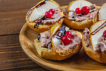 toast with chicken liver pate with pear, cranberry and sauce on a wooden plate