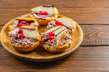 toast with chicken liver pate with pear, cranberry and sauce on a wooden table