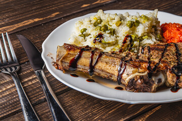 steak entrecote on the bone with rice and vegetables on a white plate