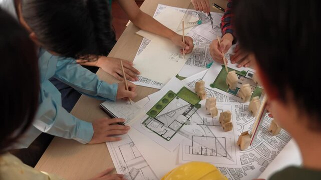 Architect and safety engineer discussion about building construction use blueprint on table with architectural document, measurement tool and wooden block scatter around at modern office. Delineation.