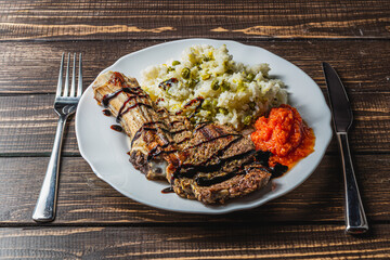 steak entrecote on the bone with rice and vegetables on a white plate