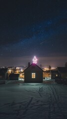 Remote winter cabin adorned with a neon pink Christmas star sits beneath the magnificent Milky Way in a dark, snowy Nordic landscape.
