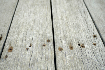 close-up detail of weathered wooden plank texture. rusty nails are embedded along the seams of the boards, adding to the aged look.