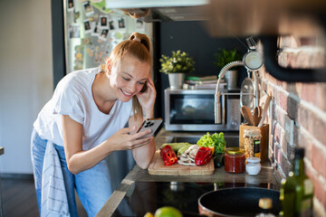 Young woman filming cooking tutorial in kitchen with fresh vegetables and eggs