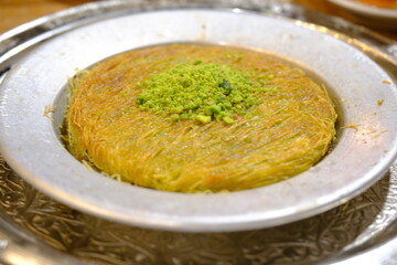 Kunefe and kadayıf dessert, traditional flavors of Turkish cuisine. Close-up images of kunefe with pistachios served on copper. Presentation in copper containers. Traditional Turkish desserts.