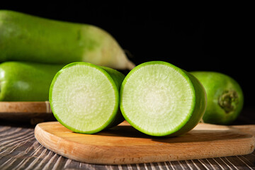 fresh green radish with half on table.