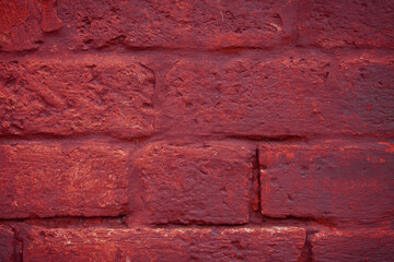 A fragment of a red brick wall with pronounced texture. Natural age defects in the form of cracks and abrasions. Rough surface with traces of dried paint.