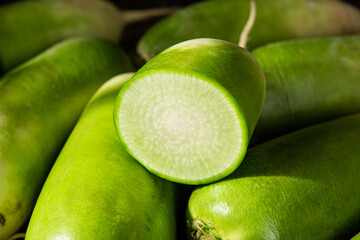 fresh green radish with half on table.