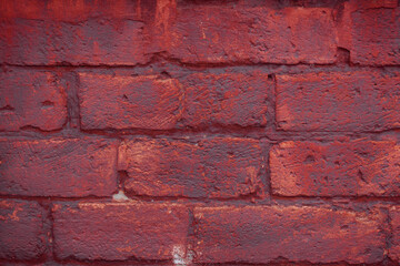 A fragment of a red brick wall with pronounced texture. Natural age defects in the form of cracks and abrasions. Rough surface with traces of dried paint.