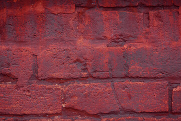 A fragment of a red brick wall with pronounced texture. Natural age defects in the form of cracks and abrasions. Rough surface with traces of dried paint.