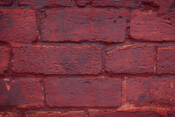 A fragment of a red brick wall with pronounced texture. Natural age defects in the form of cracks and abrasions. Rough surface with traces of dried paint.