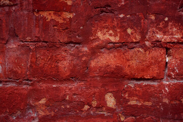 A fragment of a red brick wall with pronounced texture. Natural age defects in the form of cracks...